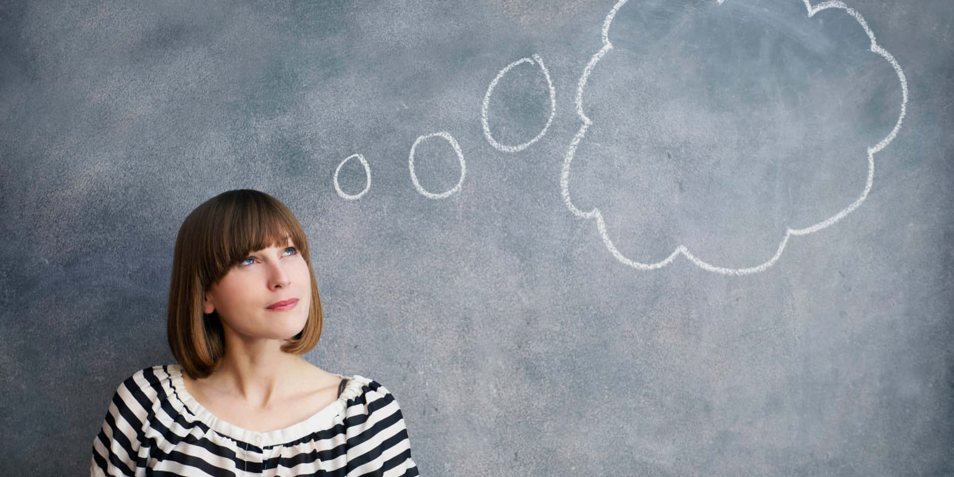 Young Woman Thinking With Thought Bubble Over Chalkboard
