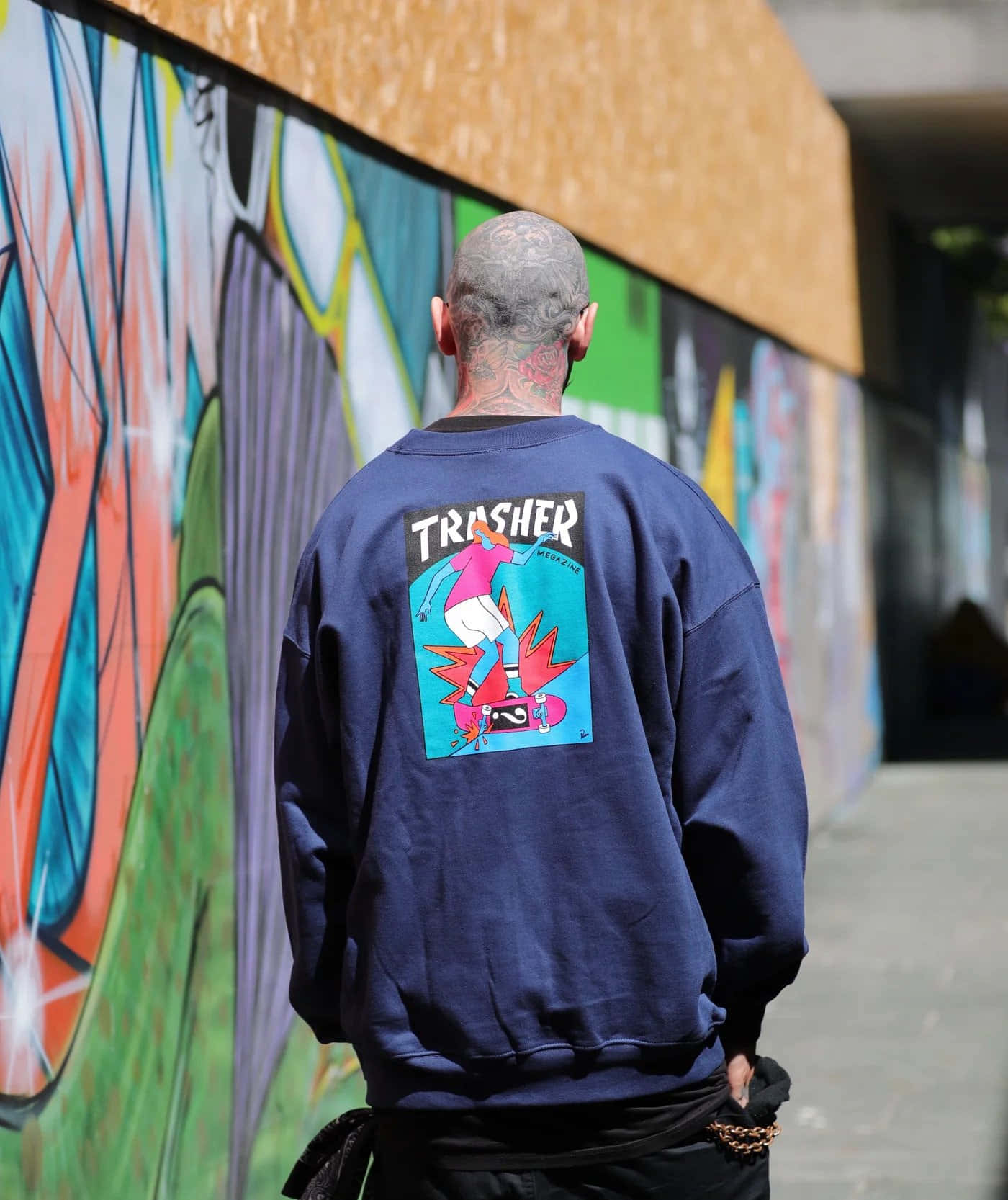 A Man Walking Down A Street With Graffiti On His Sweatshirt