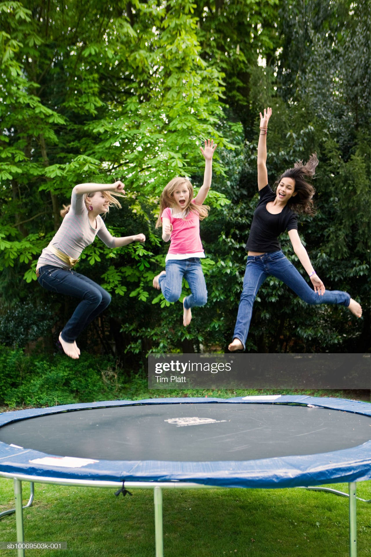 Three young girls enjoying jumping on a trampoline. Wallpaper