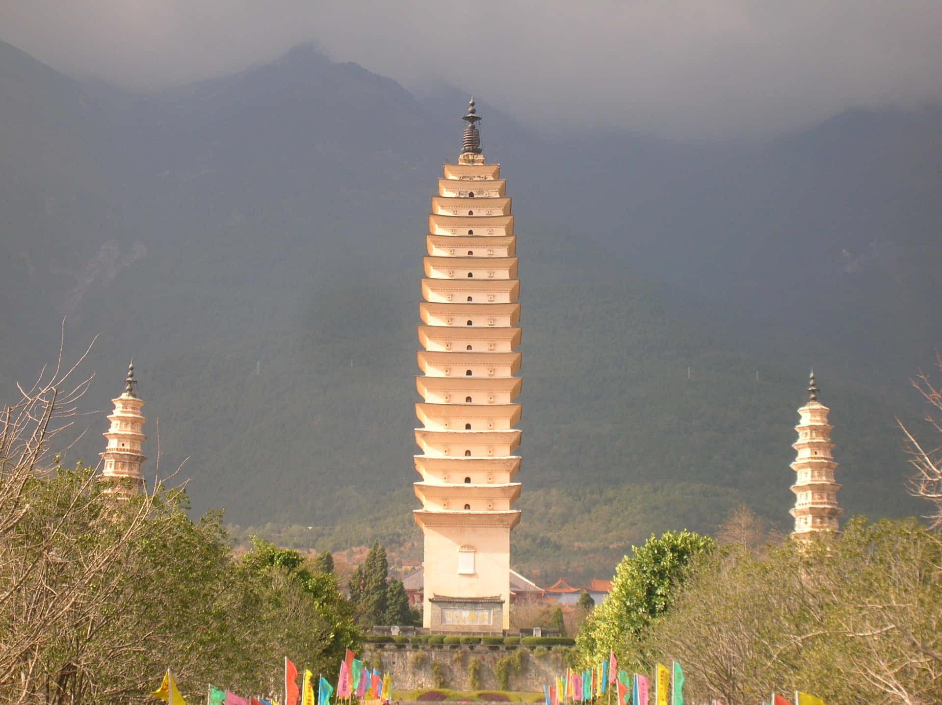 The Enchanting Three Pagodas Adorned with Colorful Prayer Flags Wallpaper