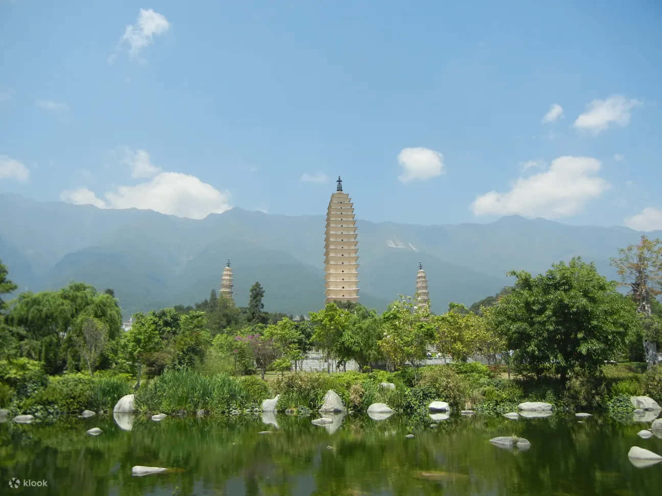 Tre pagoder med sten på en flod, der løber igennem et område af træer Wallpaper