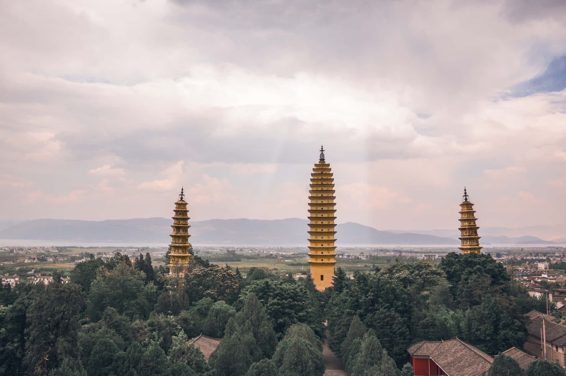 Three Pagodas With Sun Behind Clouds Wallpaper