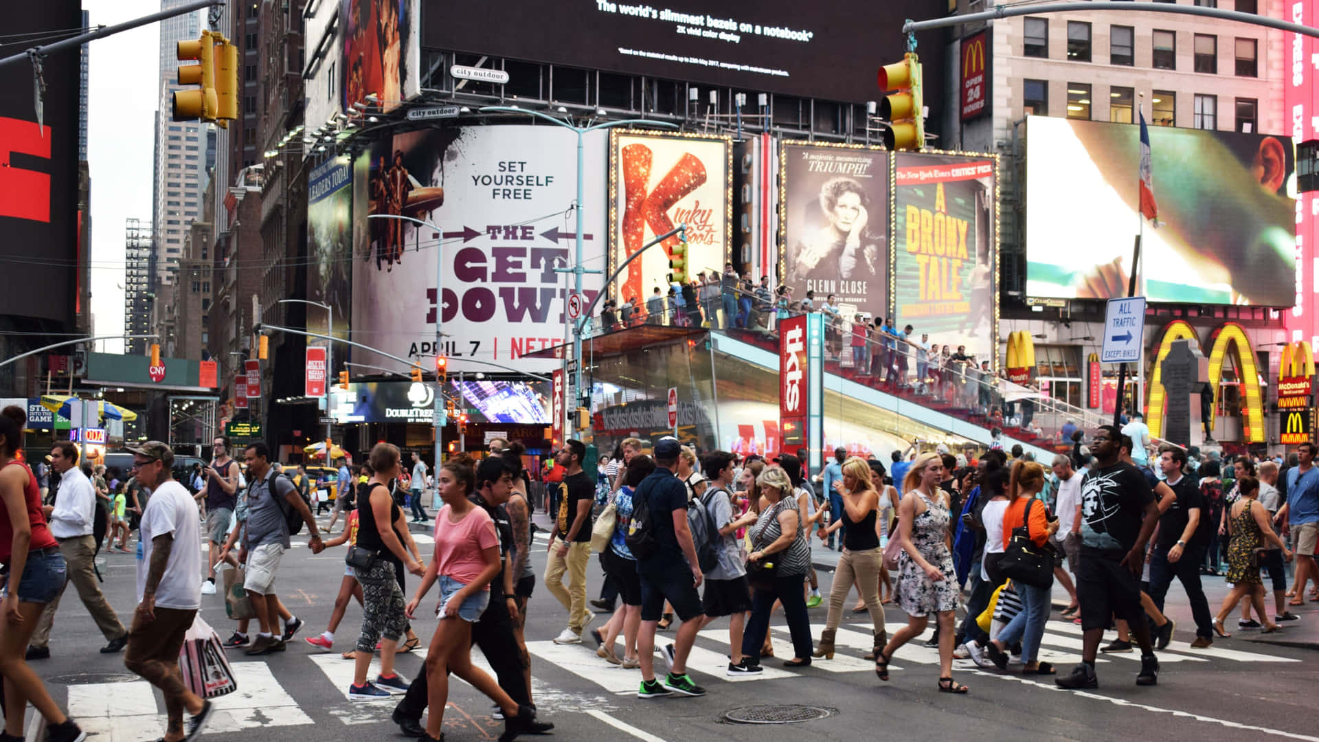 A Crowd Of People Crossing A Busy Street In Times Square Wallpaper