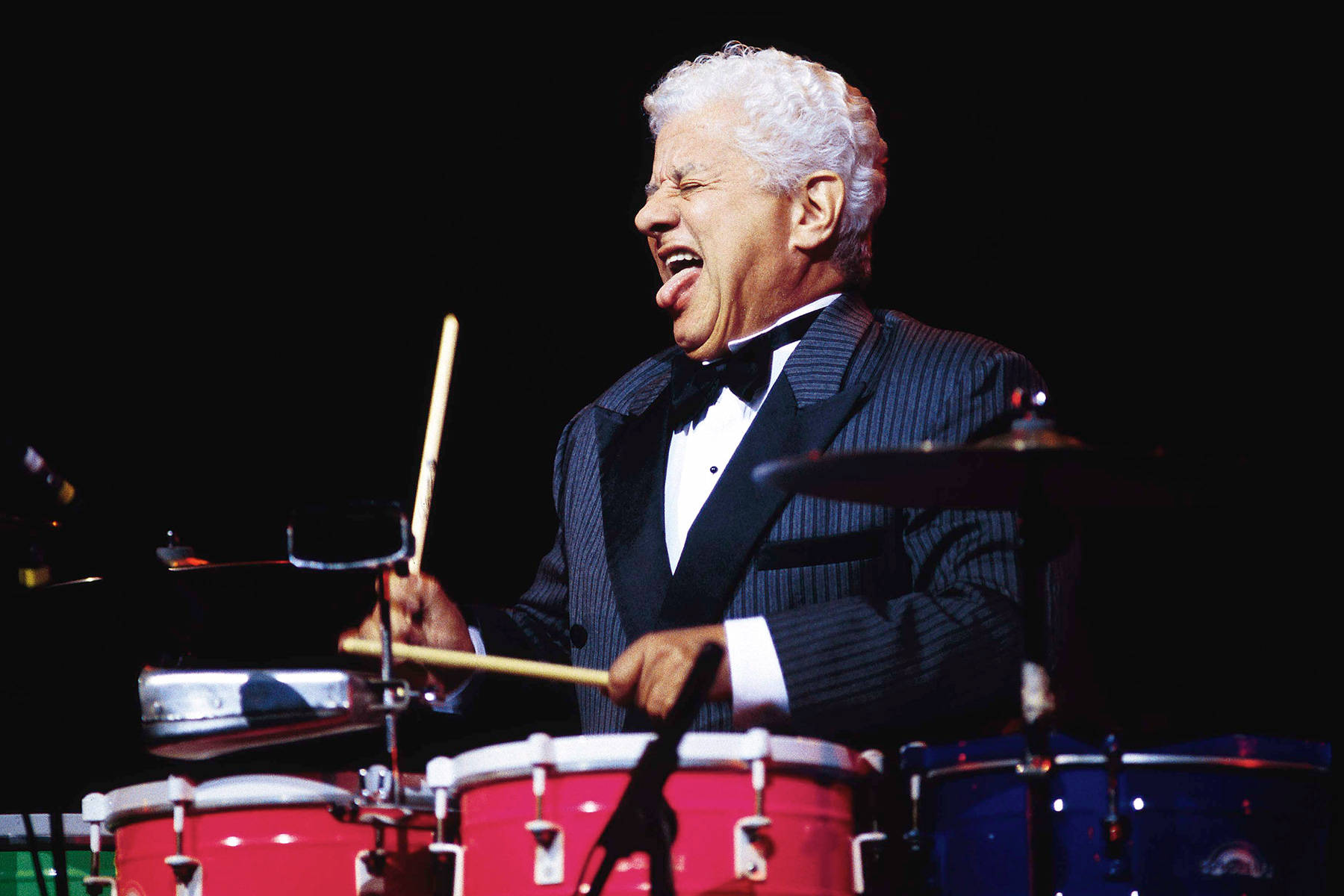Tito Puente Tongue Out While Playing Drums Wallpaper