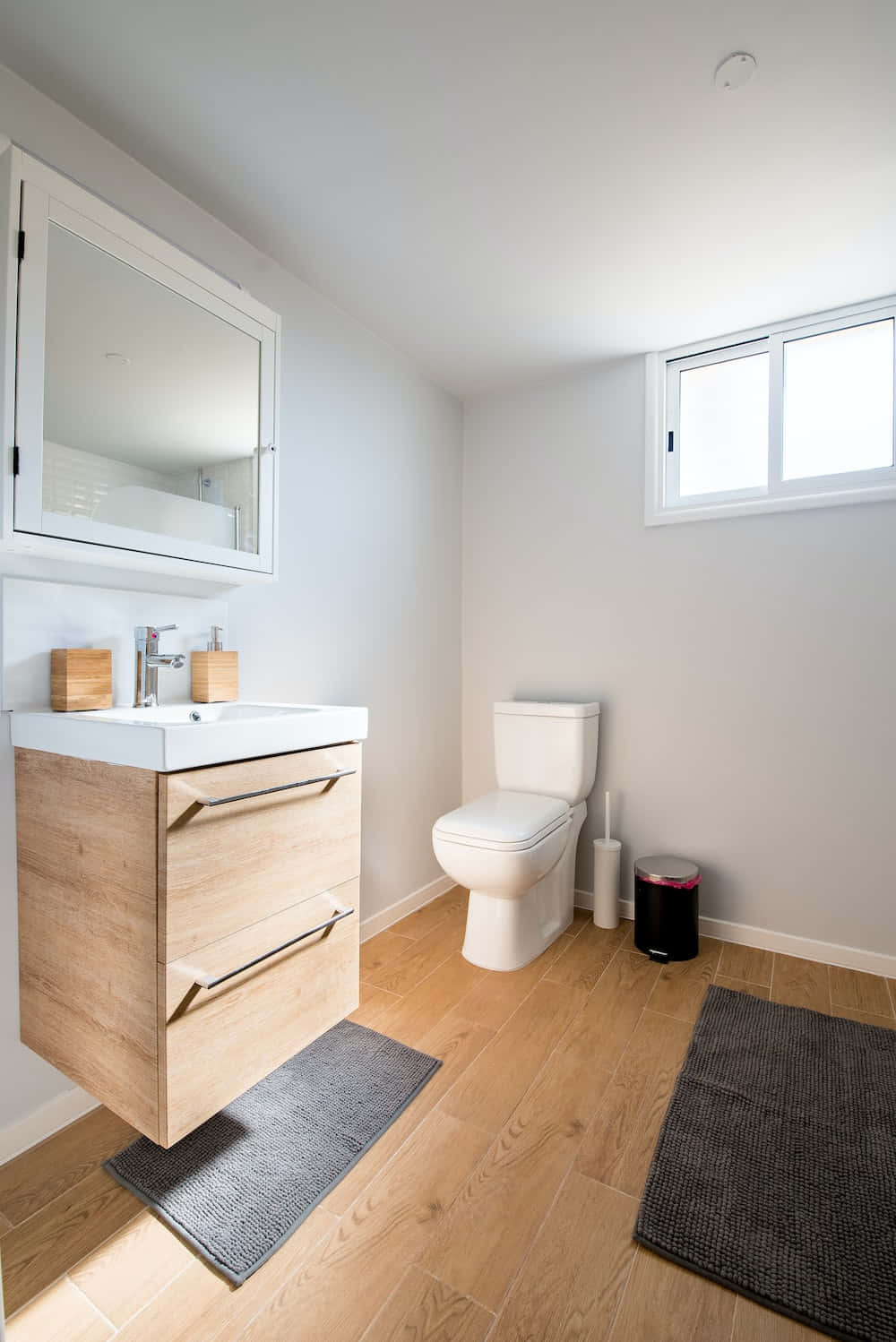 A Bathroom With A Toilet, Sink, And A Window