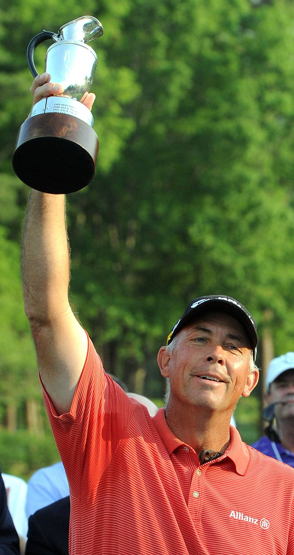 Professional golfer Tom Lehman victorious with trophy overhead Wallpaper