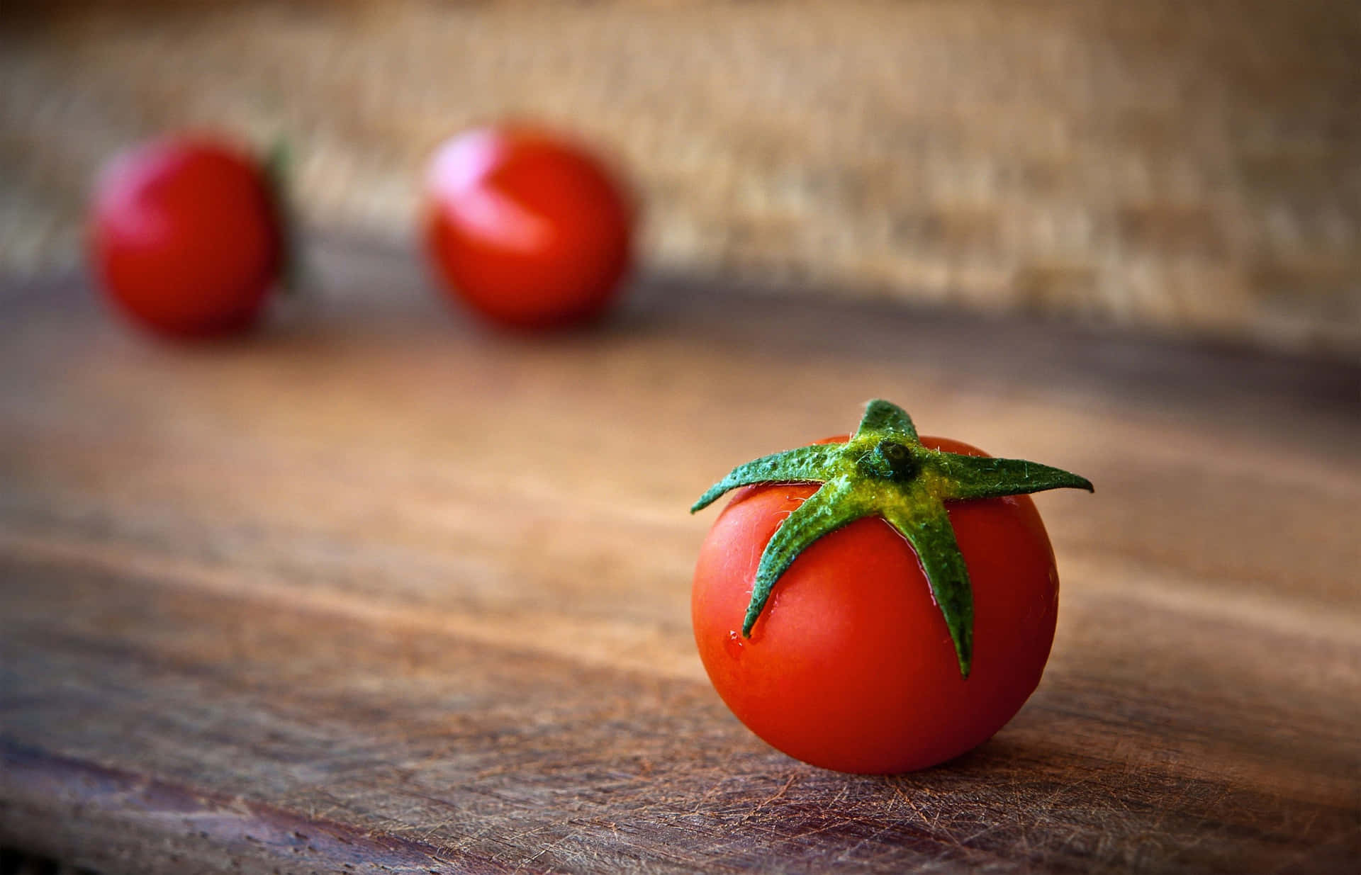 Three Tomatoes On A Wooden Board