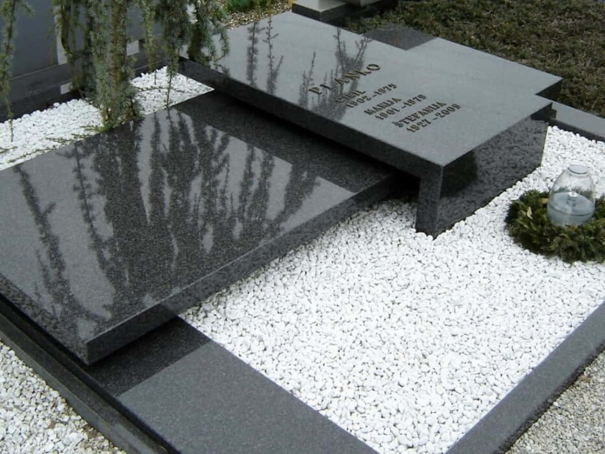 A Black Granite Gravestone With A Flower Bed