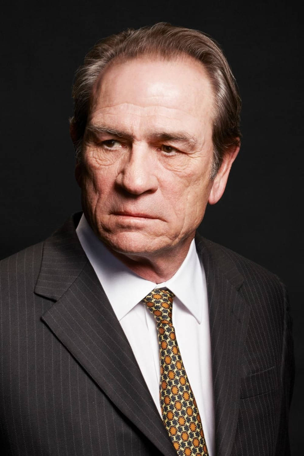 Caption: Portrayal of Tommy Lee Jones in a Thoughtful Indoor Headshot Wallpaper