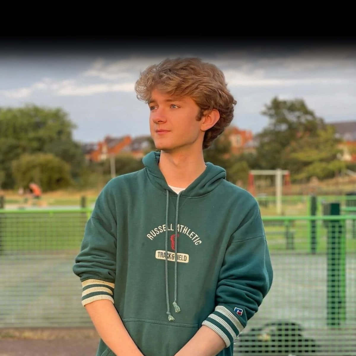 A Young Man In A Green Hoodie Standing On A Tennis Court