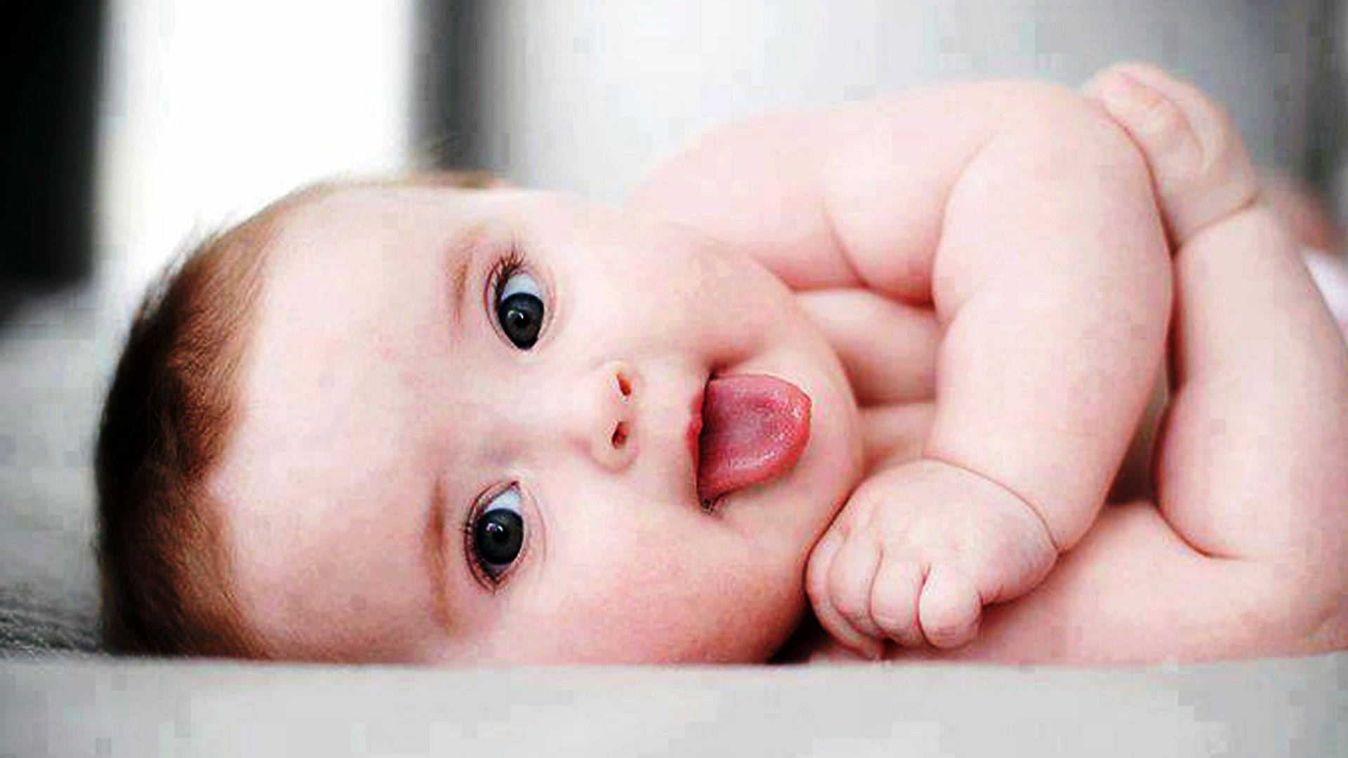 A cute baby, ready for fun with his tongue out Wallpaper