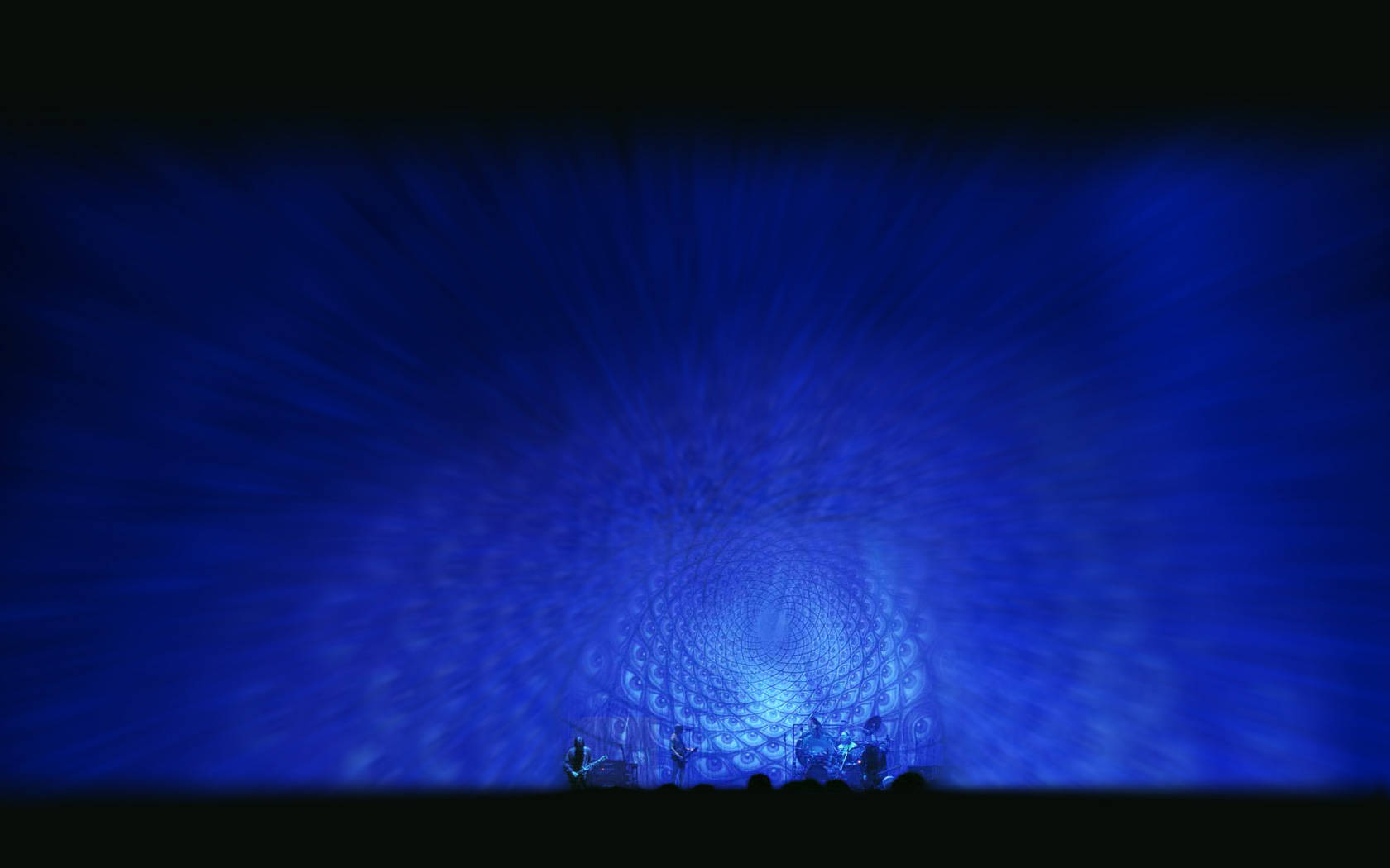 Iconic Rock Band Tool Against a Mesmerizing Blue Eye Pattern Wallpaper