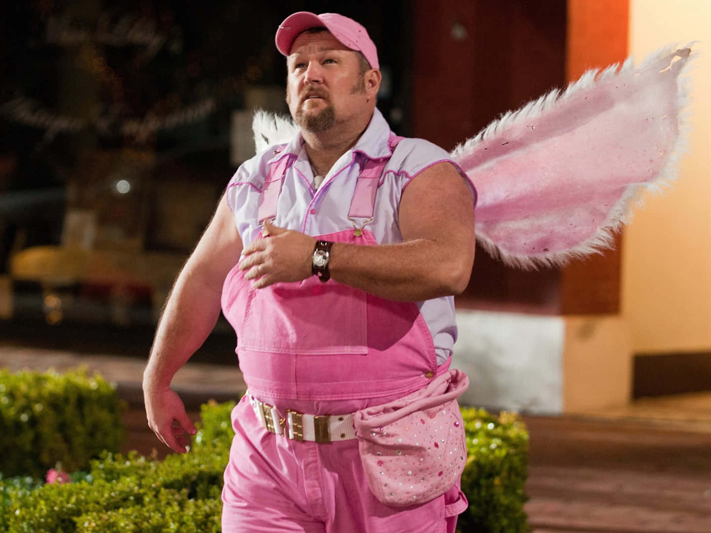 A Man Dressed In Pink With Wings Walking Down The Street