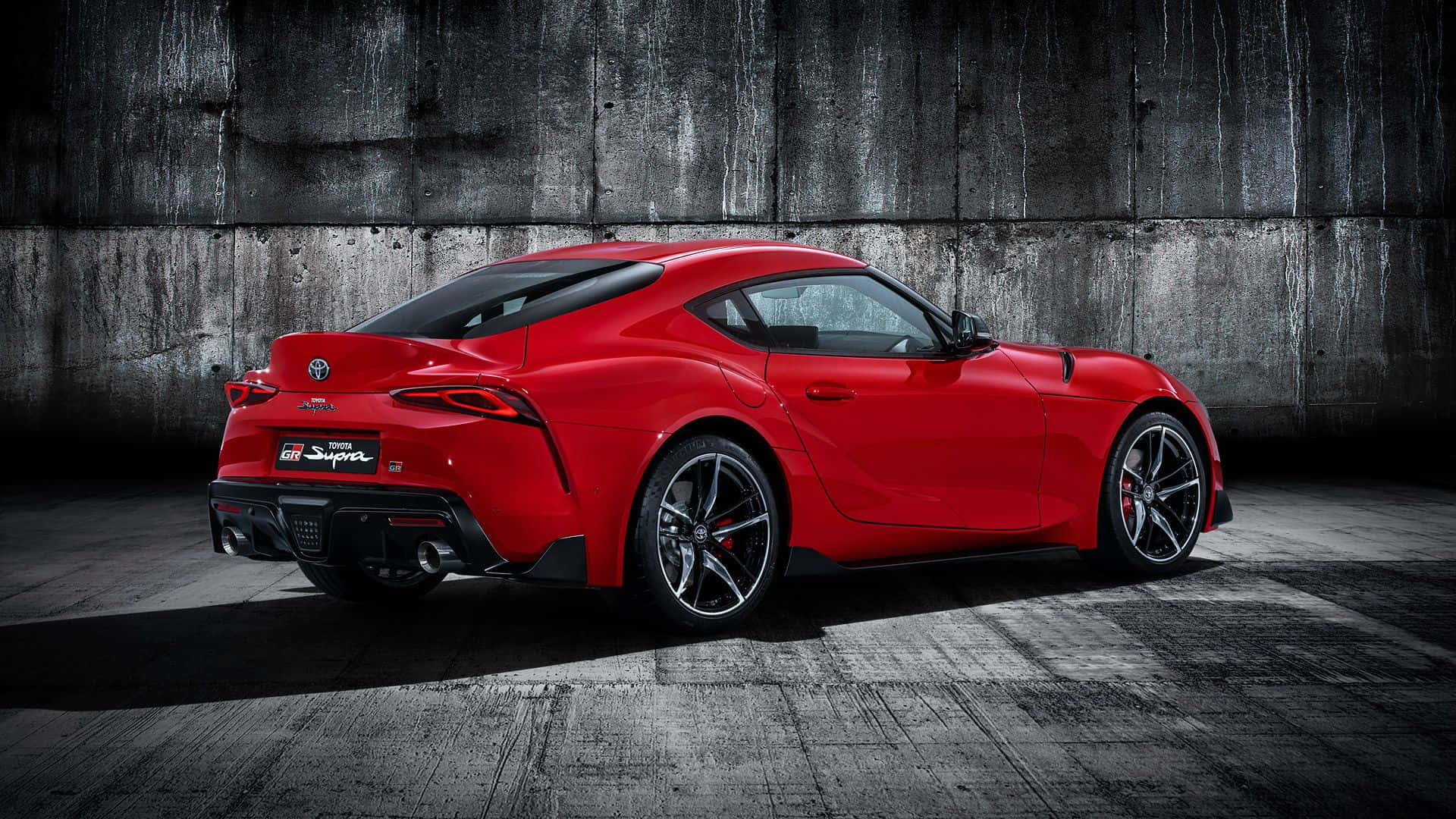 The Red Toyota Supra Is Parked In A Dark Room