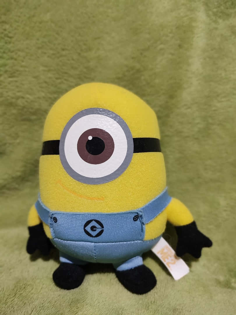 Unpeluche De Un Minion Está Sentado Sobre Un Fondo Verde.