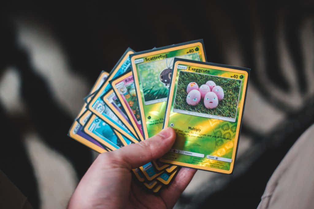 Pokemon Cards In A Hand Holding Them Up