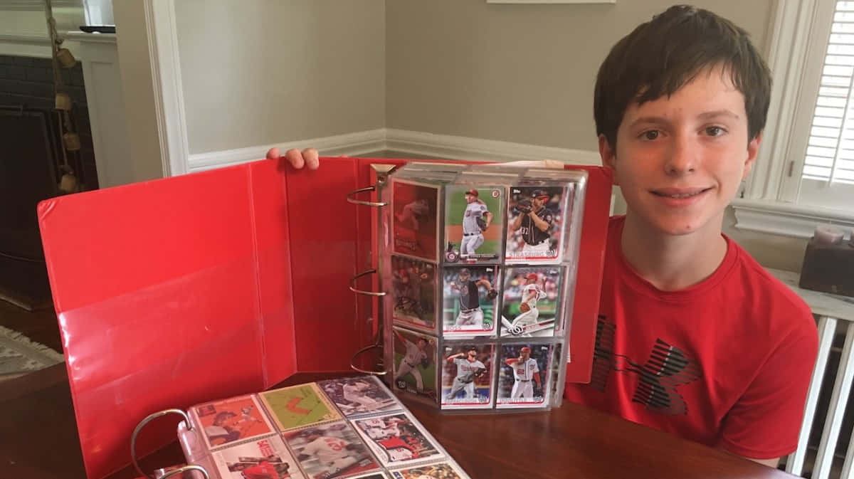 A Boy Holding A Red Binder Full Of Cards