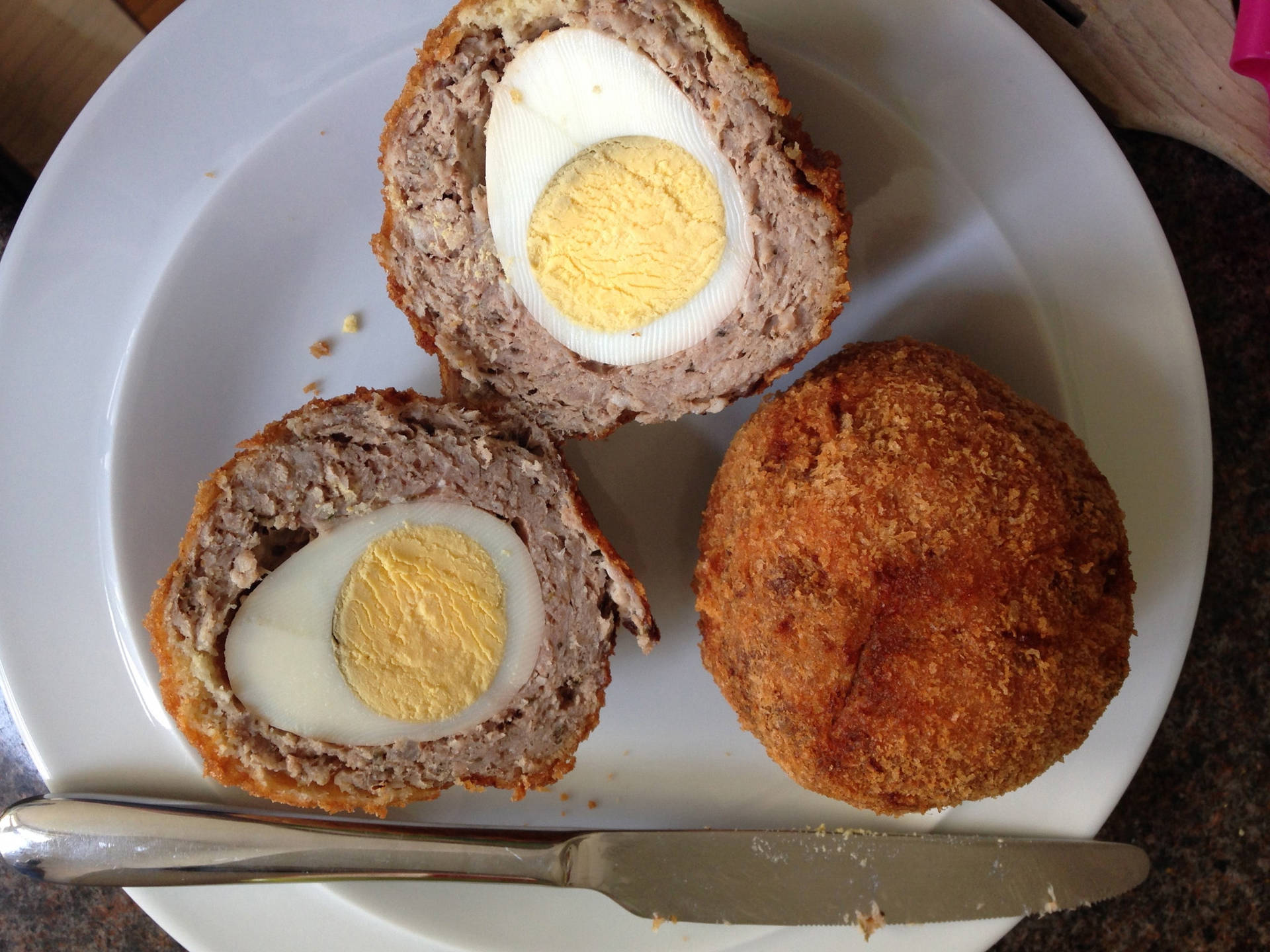 Tradionelt britisk scotch æg ret med middag kniv siddende på en gammel brændt duge. Wallpaper