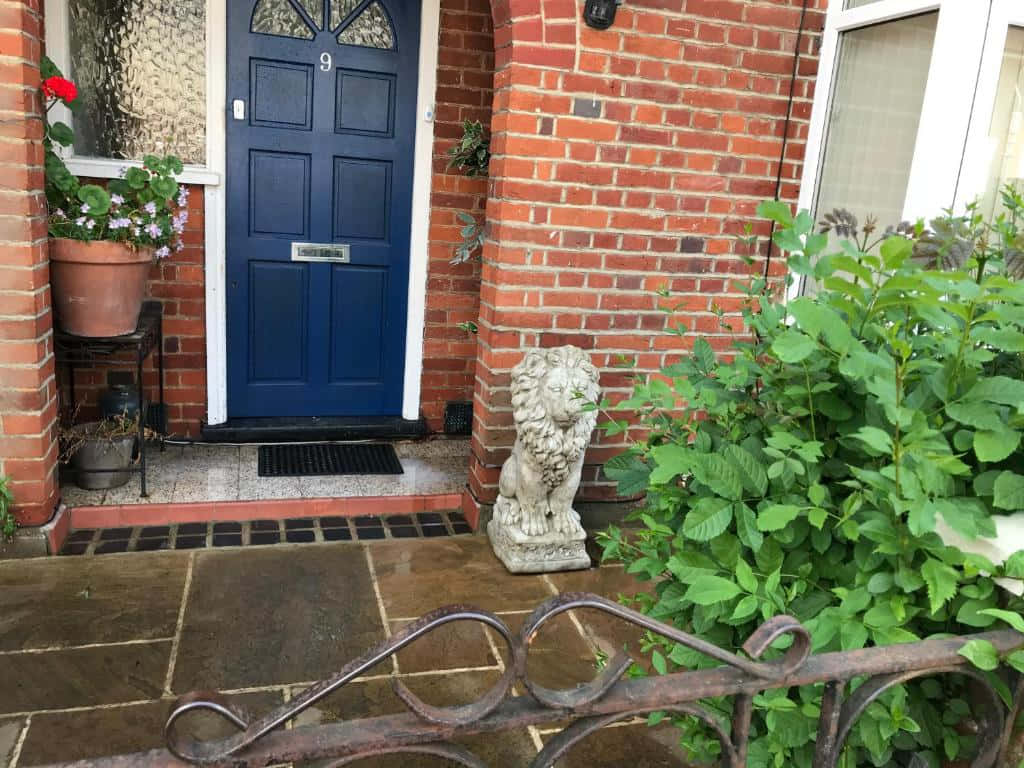 Traditional U K Home Entrancewith Blue Doorand Lion Statue Wallpaper