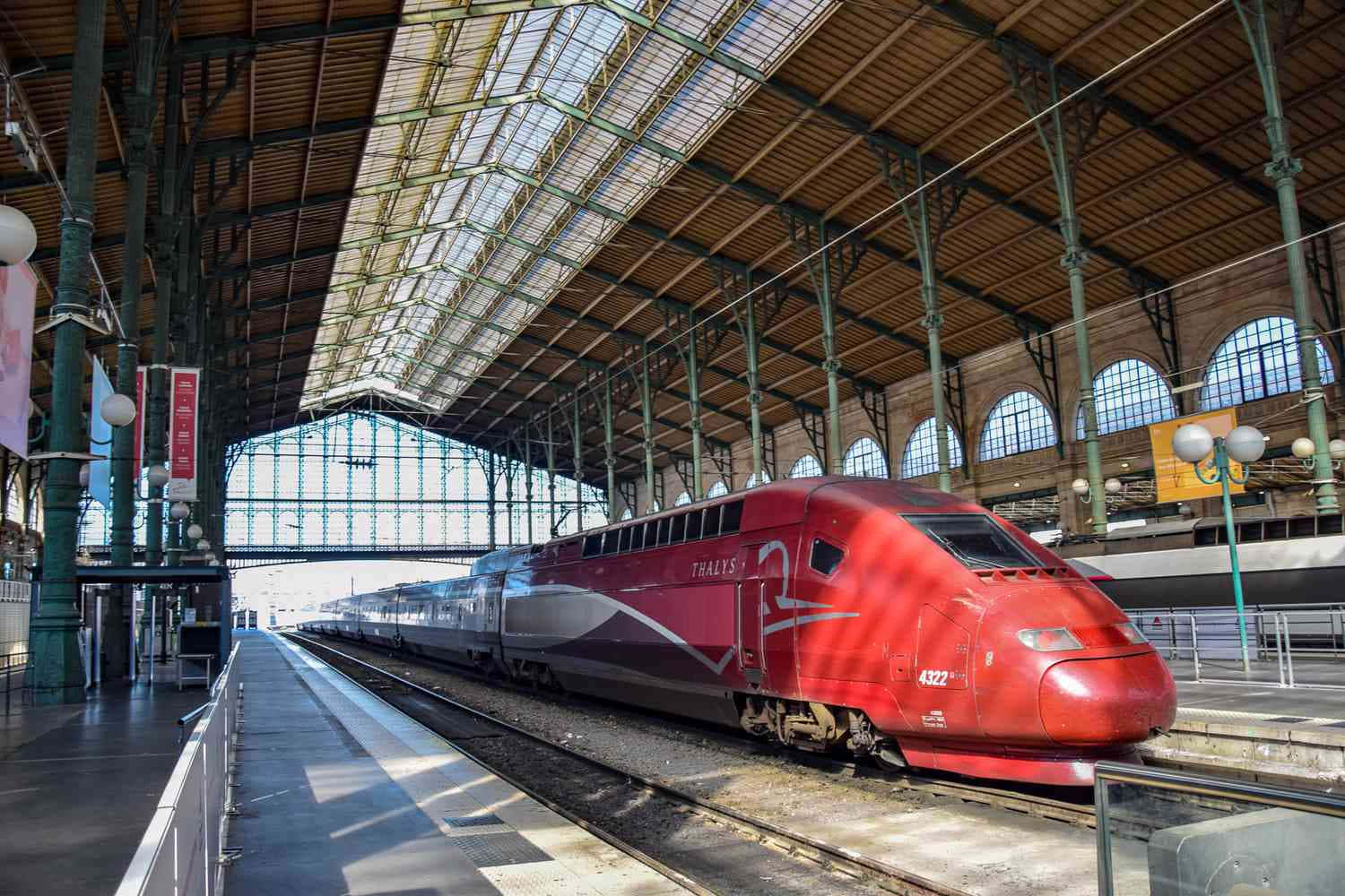 A Red Train Is In A Station With A Glass Roof
