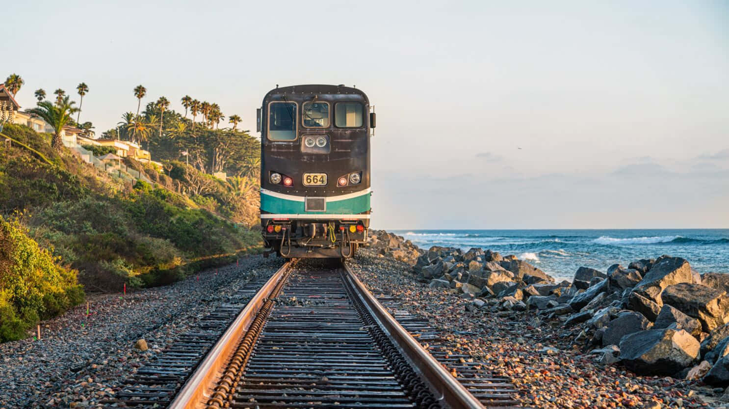 A Train Traveling Along The Tracks Near The Ocean