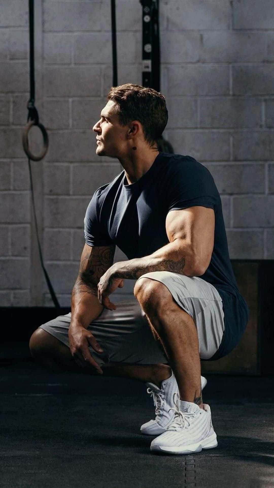 a man squatting down in a gym Wallpaper