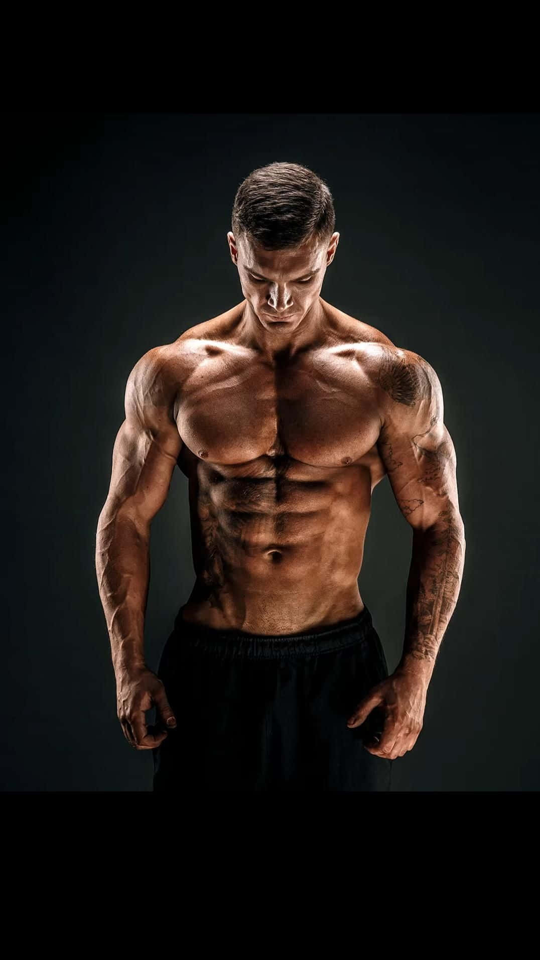 A Man With A Muscular Body Posing In Front Of A Dark Background Wallpaper