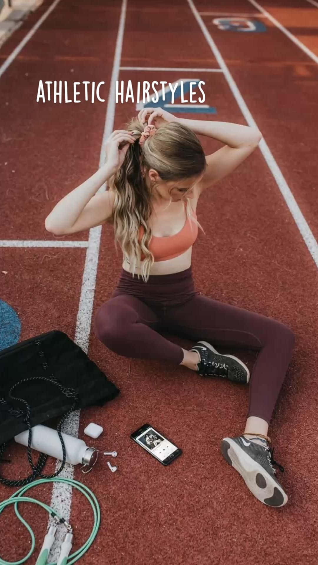 a woman sitting on a track with her phone and a hair clip Wallpaper