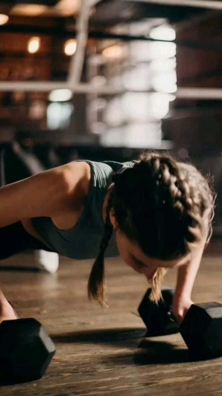 A Woman Doing Push Ups With Dumbbells Wallpaper