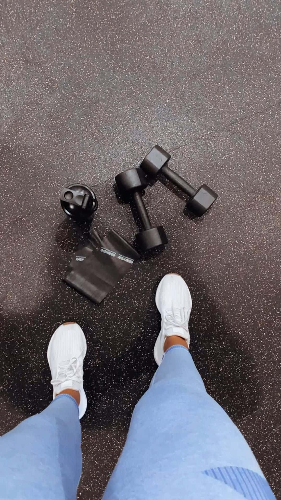 a person standing on a gym floor with dumbbells Wallpaper