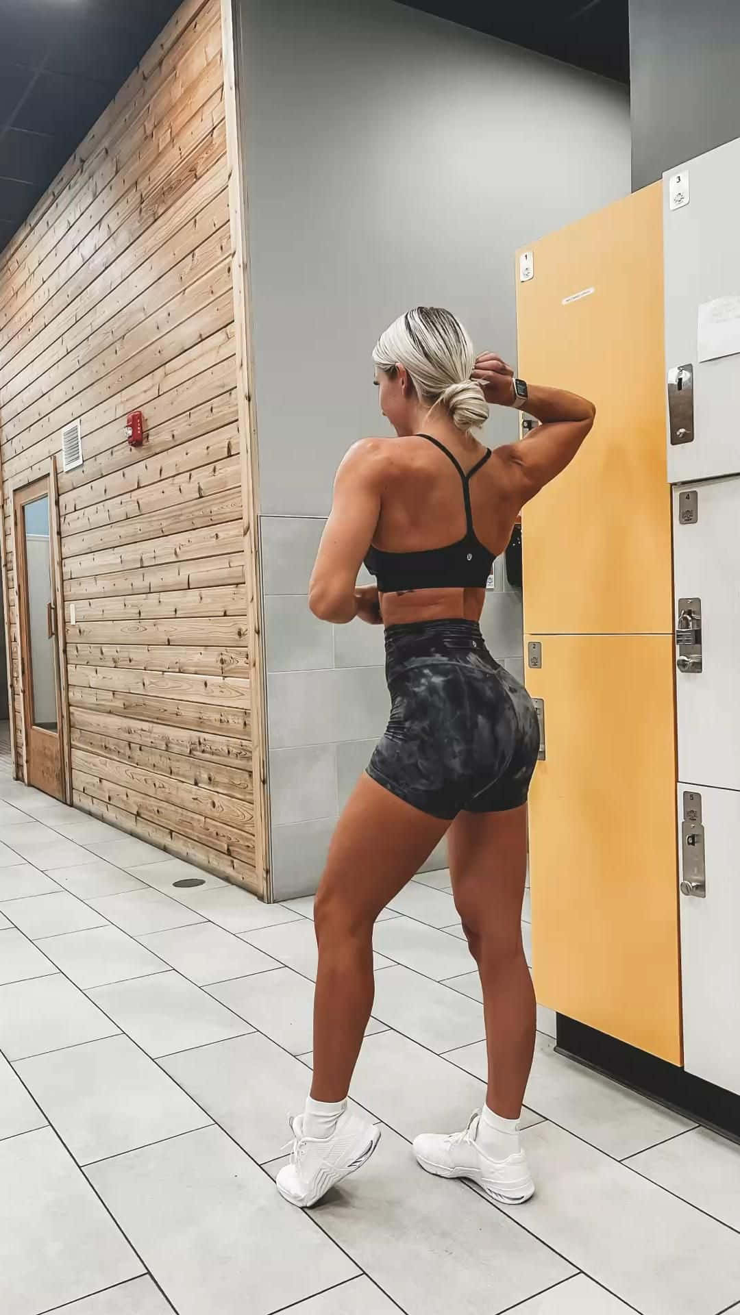 A Woman In A Gym Posing In Front Of A Locker Wallpaper