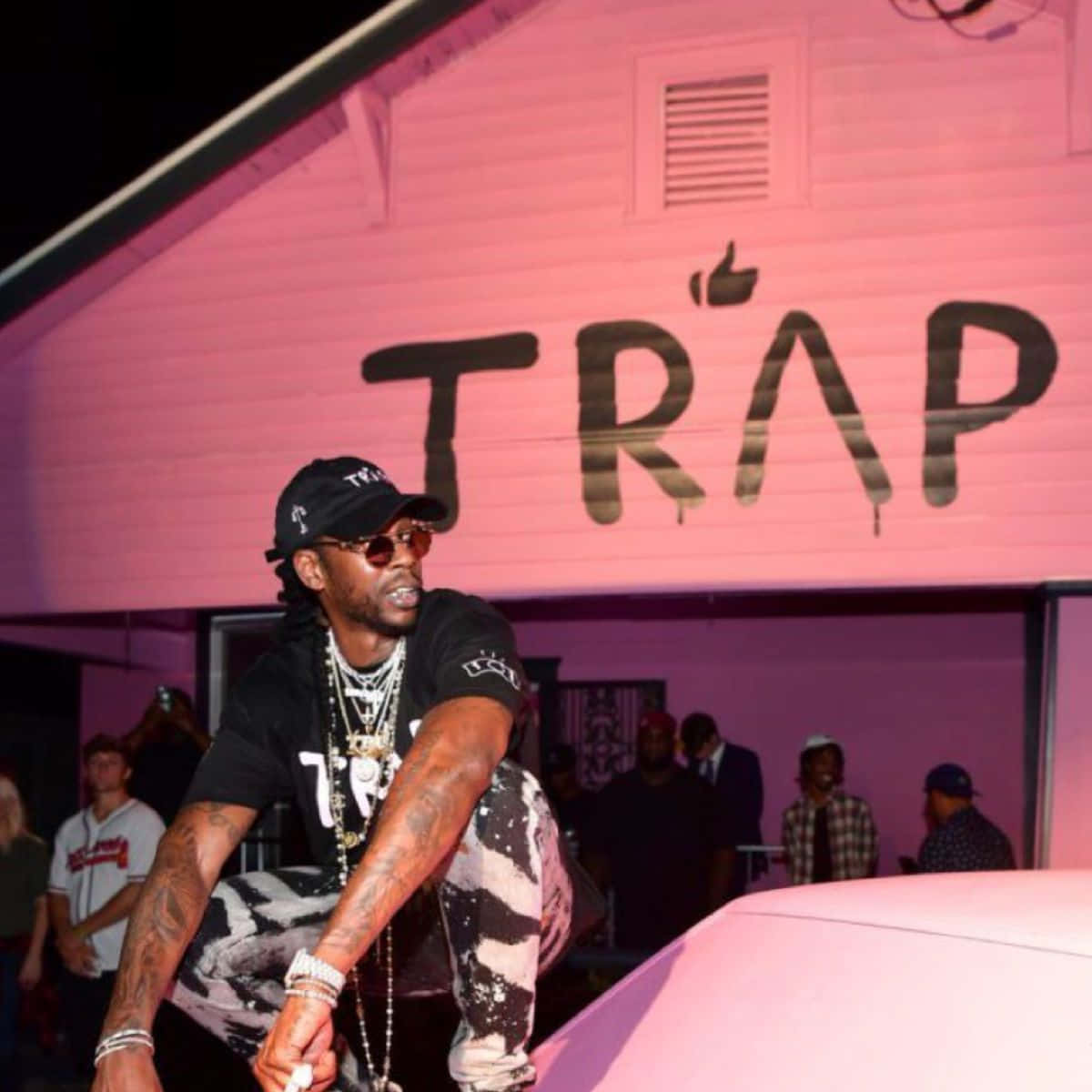 A Man Is Sitting On A Pink Car With A Sign That Says Trap Wallpaper