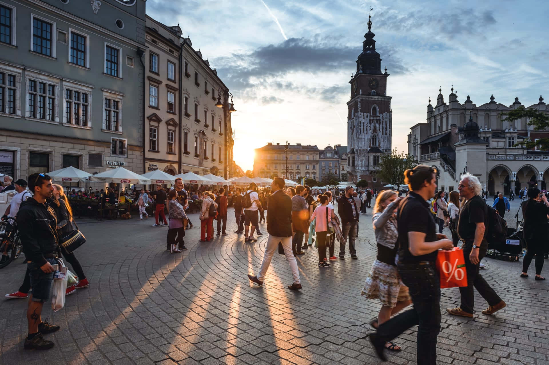 A City Square With People Walking Around At Sunset Wallpaper