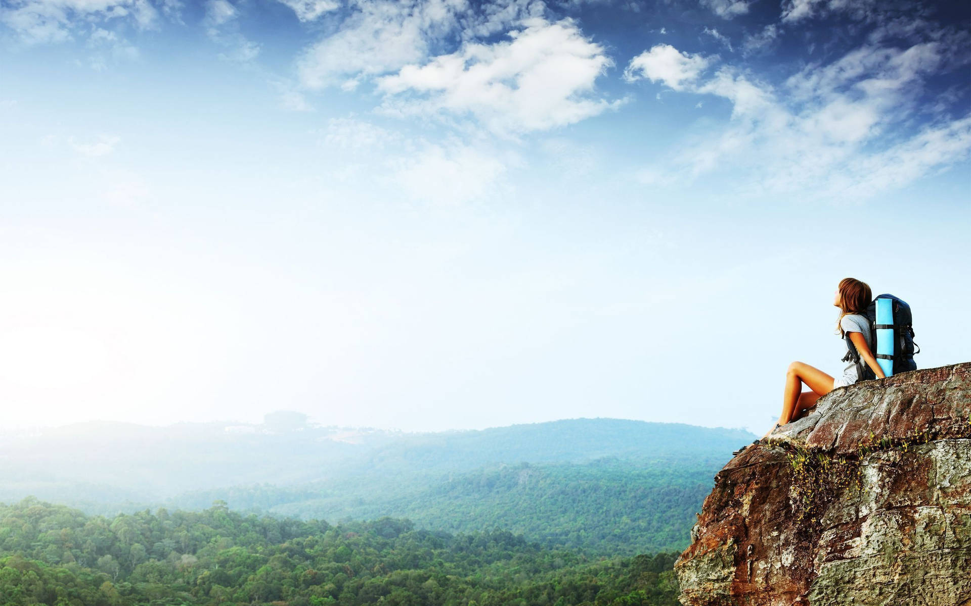 Kvinde sidder på en klippe med udsigt til et bjerg Wallpaper