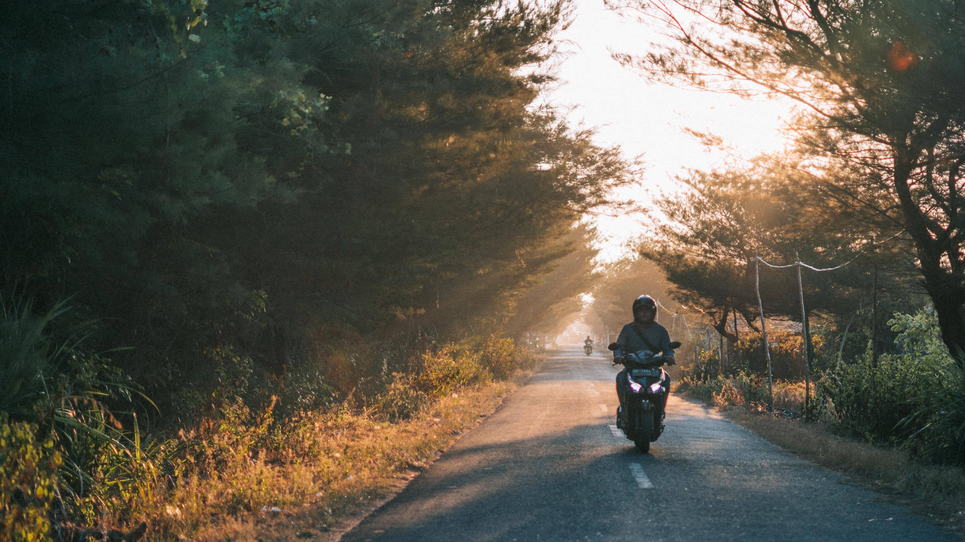 Unapersona Conduciendo Una Motocicleta Por Una Carretera. Fondo de pantalla