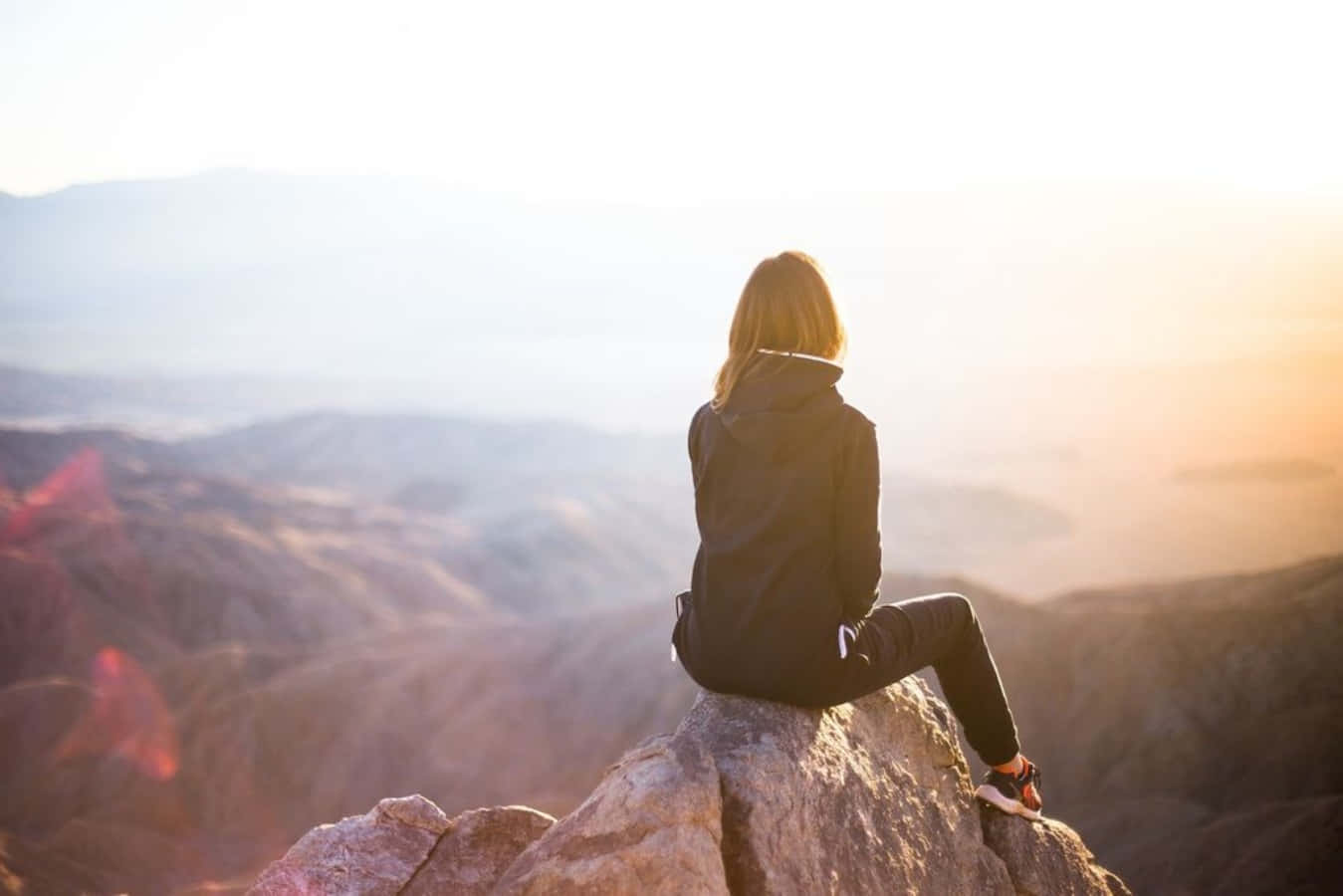 woman sitting on top of mountain at sunset