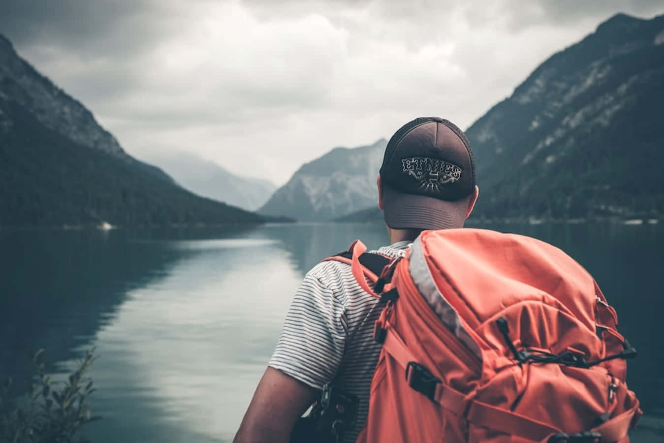 a man with a backpack looking at a lake