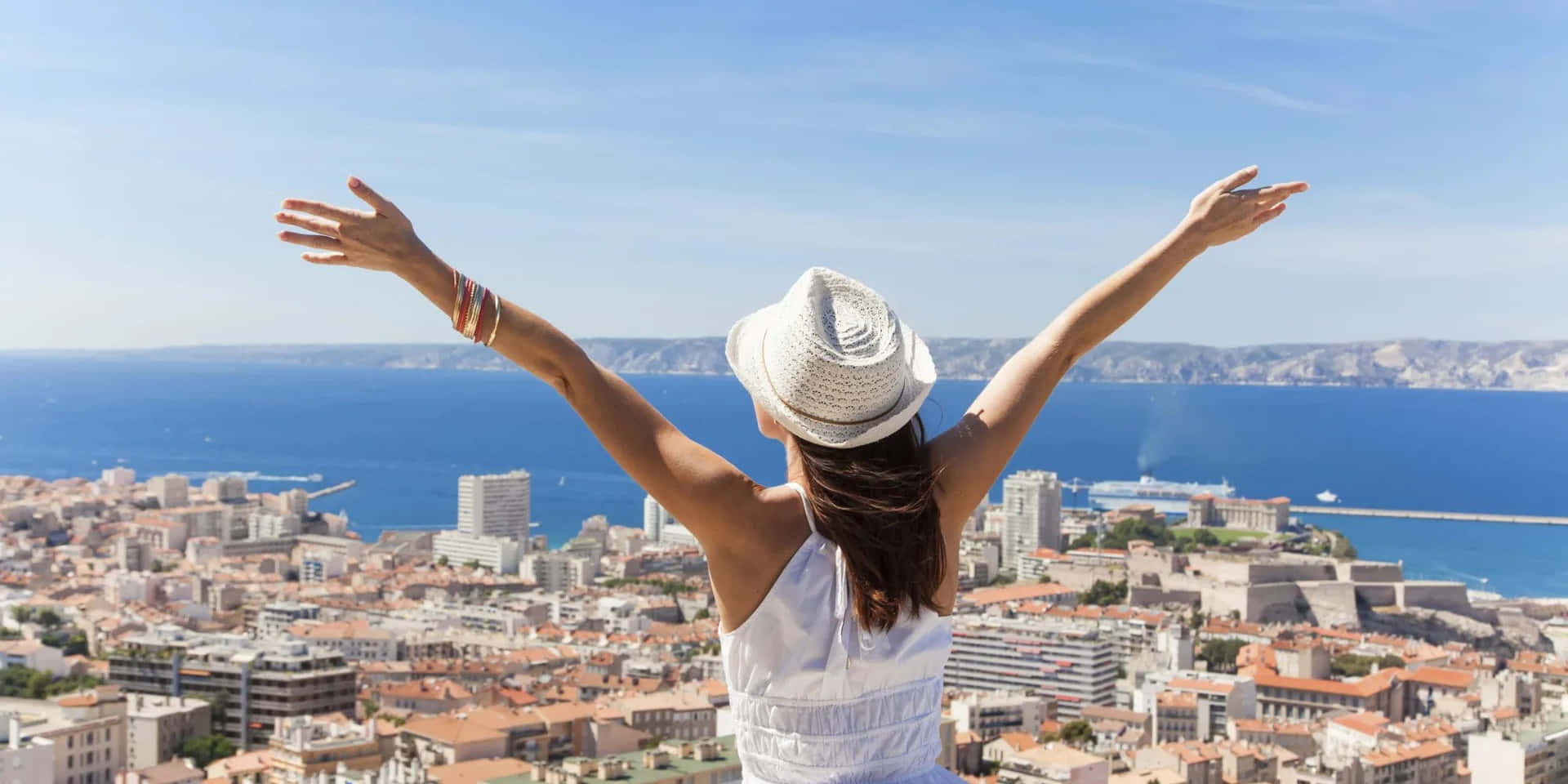 woman with arms outstretched on top of a hill overlooking the city