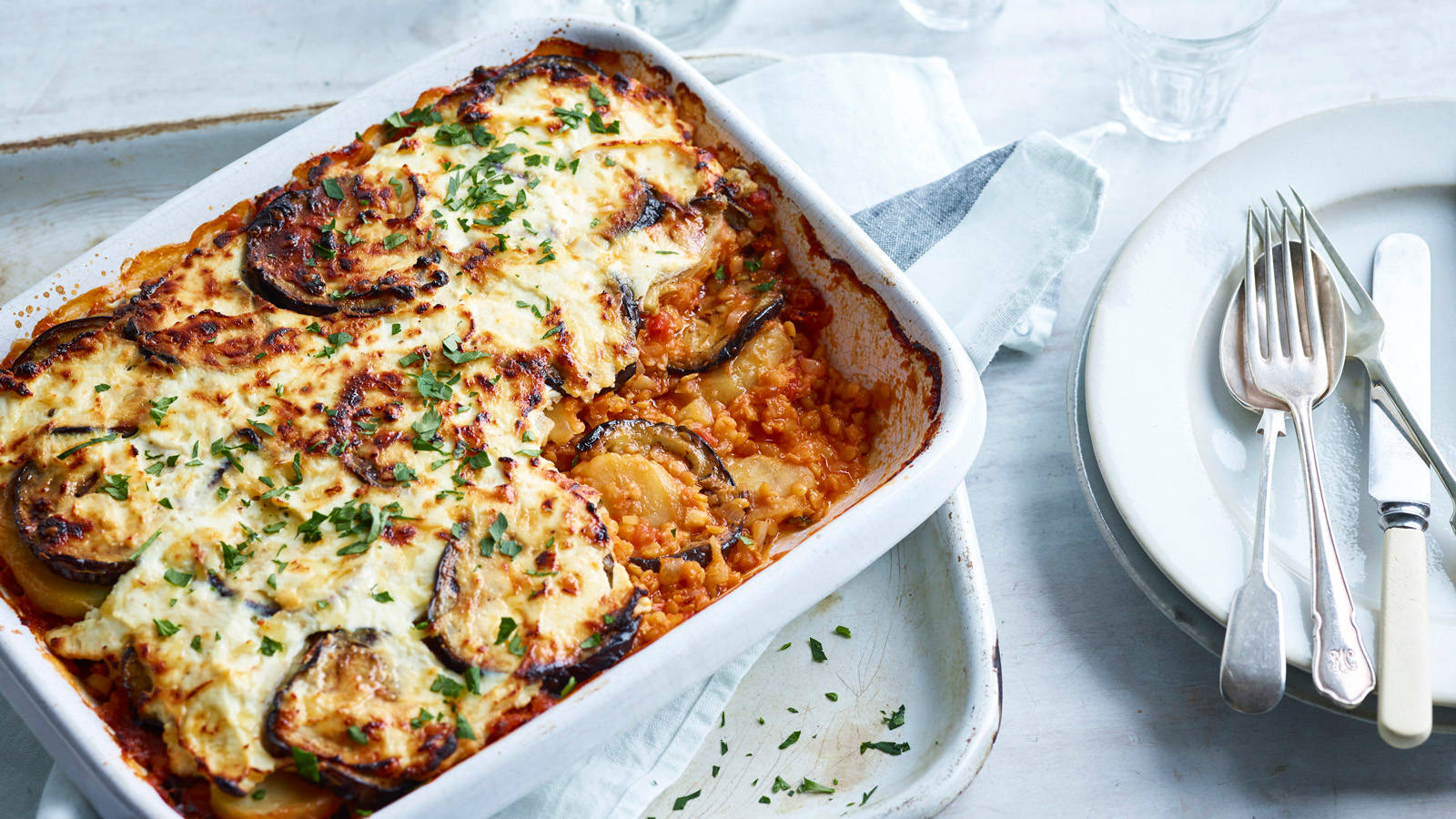 Tray Of Moussaka Near The Plates With Cutlery Wallpaper
