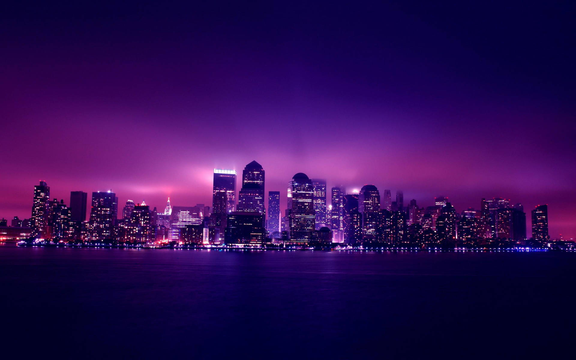 A Purple Skyline With Lights Over The Water Wallpaper