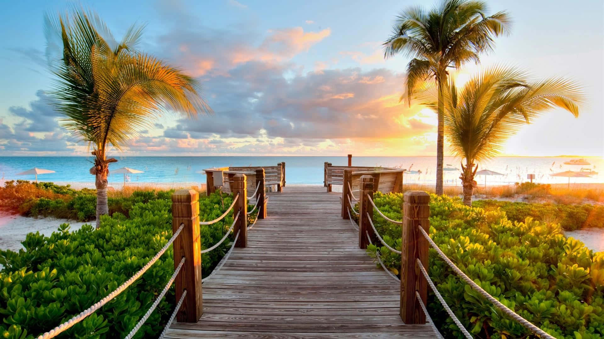 A Wooden Walkway Leading To The Beach At Sunset