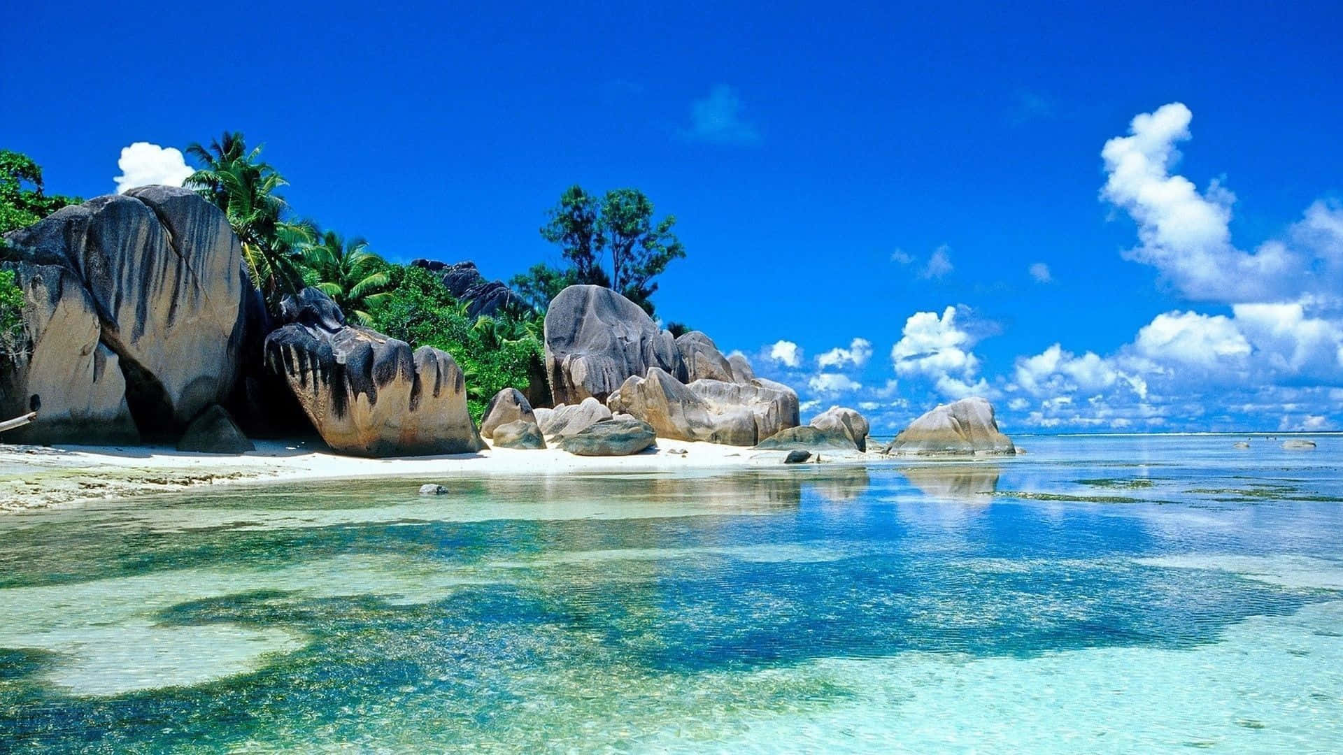 A Beach With Clear Water And Rocks Wallpaper