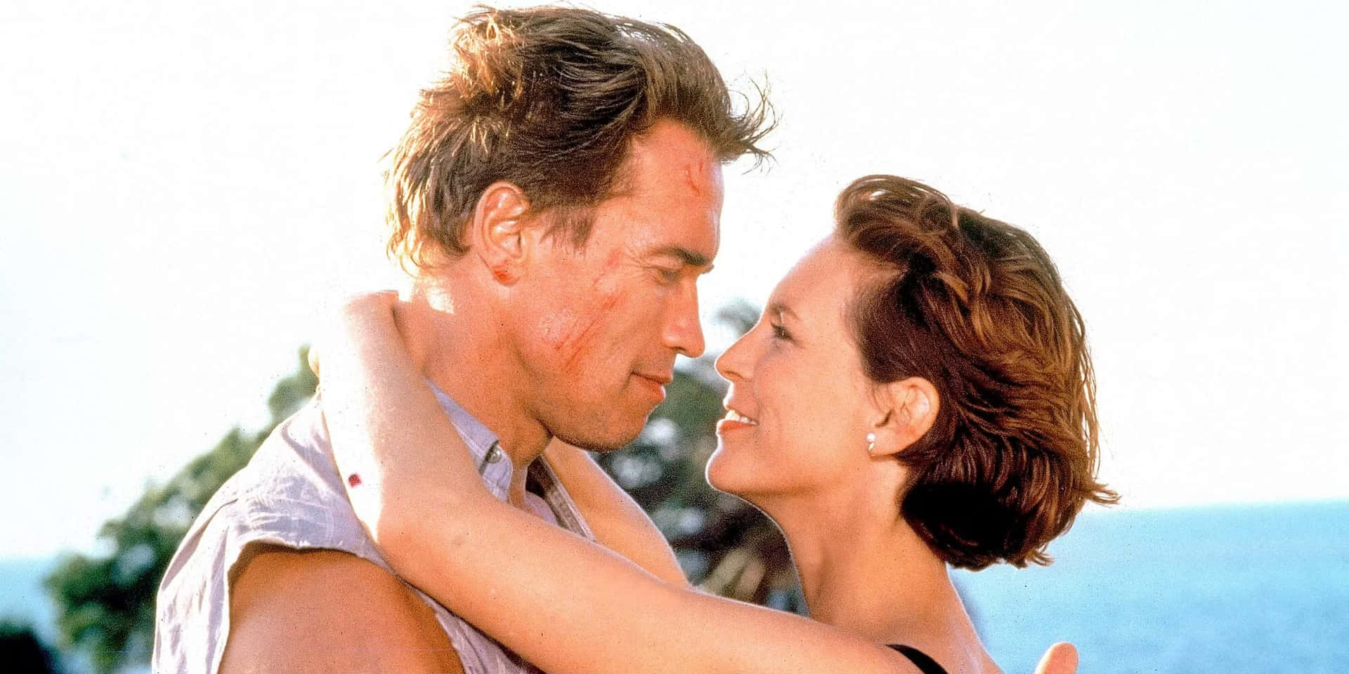 Arnold Schwarzenegger and Jamie Lee Curtis in a thrilling scene from the movie True Lies Wallpaper