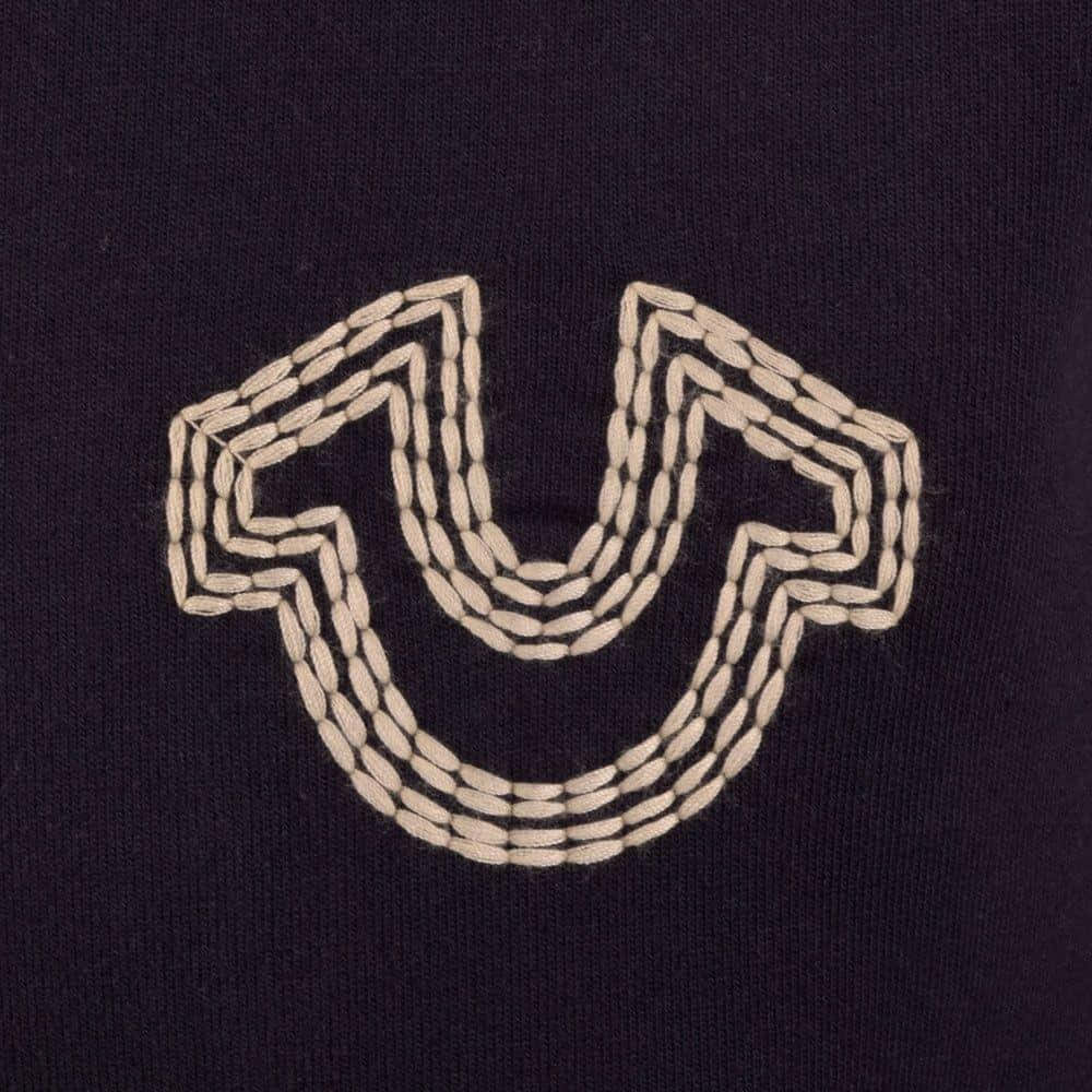 A Black Sweater With A White Embroidered U On It Wallpaper