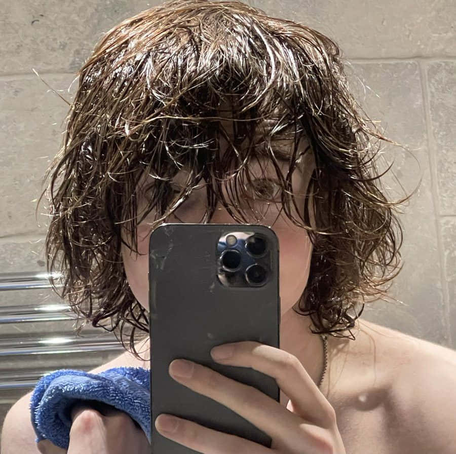 A Man With Hair Taking A Selfie With His Phone