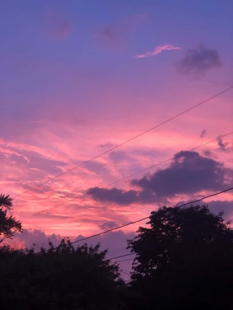 A Pink Sky With Clouds And Power Lines