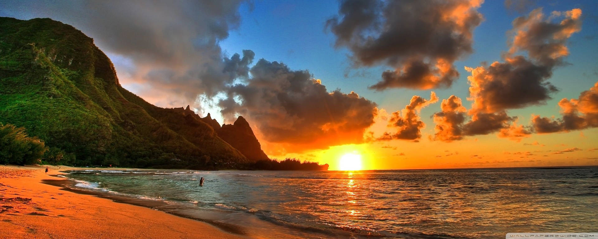 a sunset over a beach with mountains in the background Wallpaper