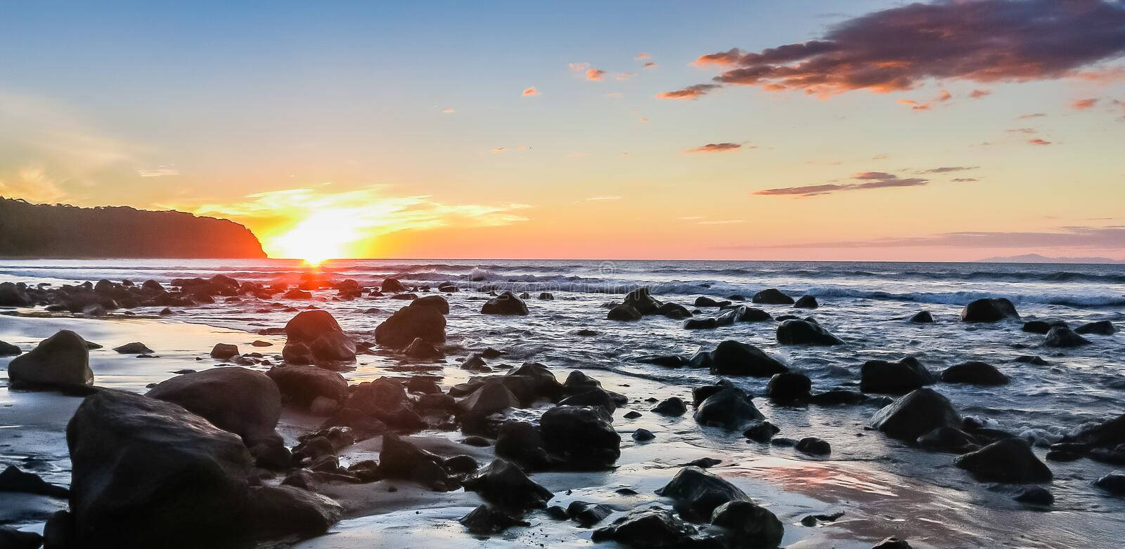 a beach with rocks and a sunset Wallpaper