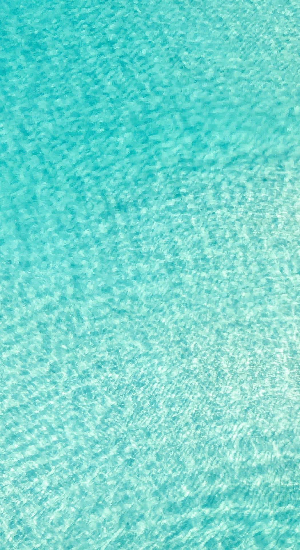 Et blåt vandoverflade med en hvid sandstrand og et par små fiskerbåde Wallpaper