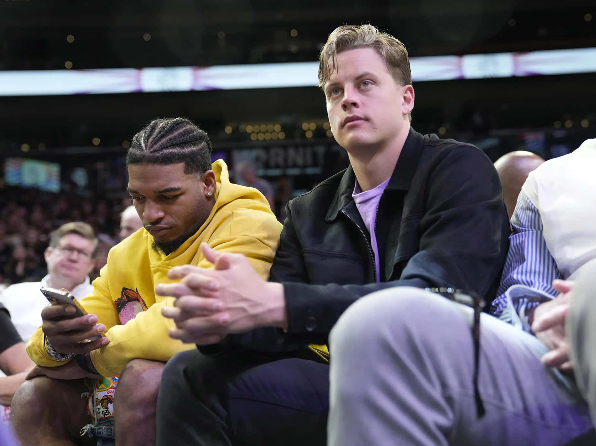 Two Men Sitting Court Sideat Sporting Event Wallpaper